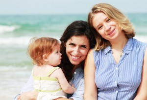 two beautiful girls with a baby on the beach